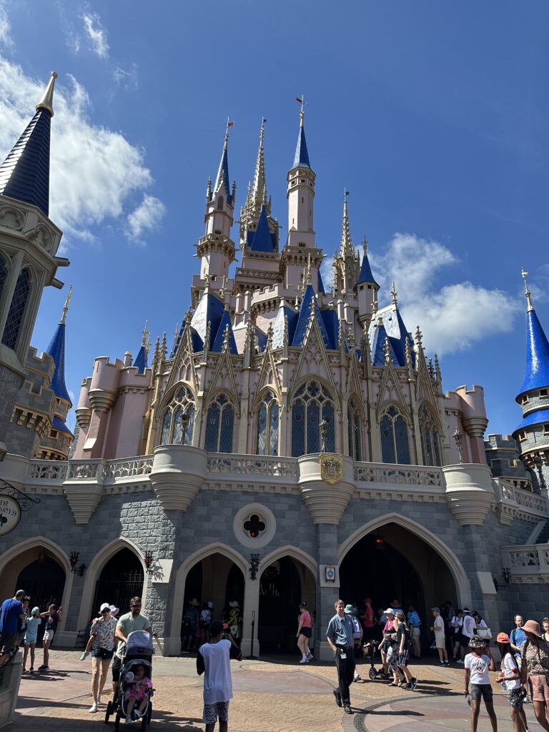 Cinderella Castle at Walt Disney World’s Magic Kingdom on a clear day with guests walking through the park